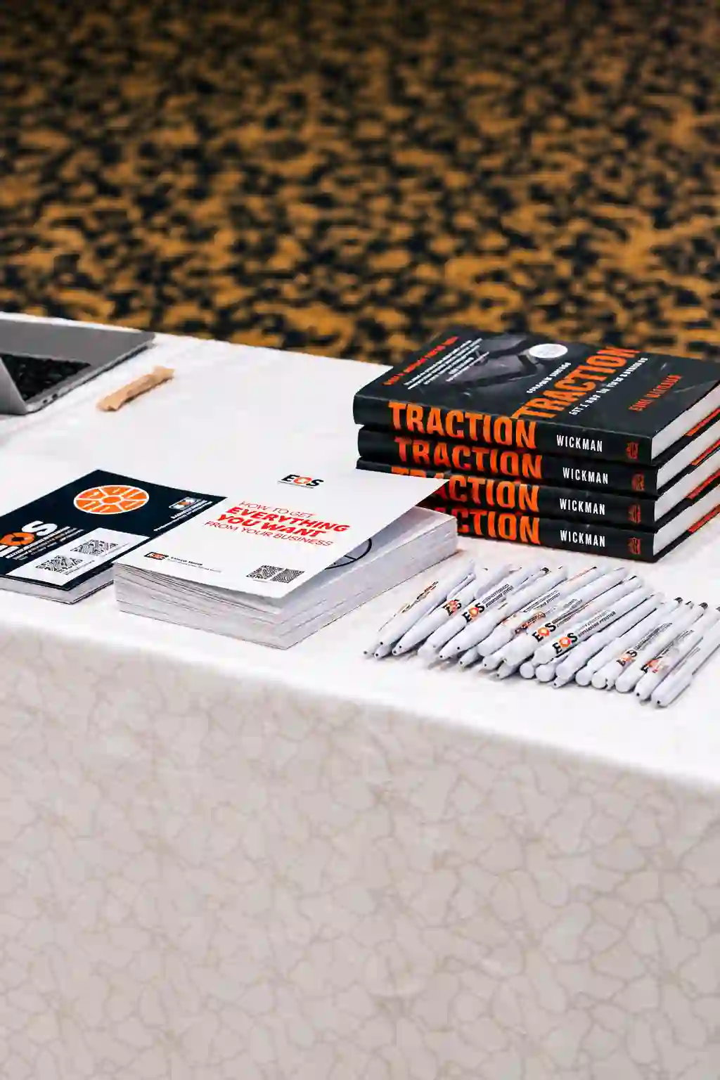 Copies of Traction by Gino Wickman and EOS® workbooks and pens on a conference table